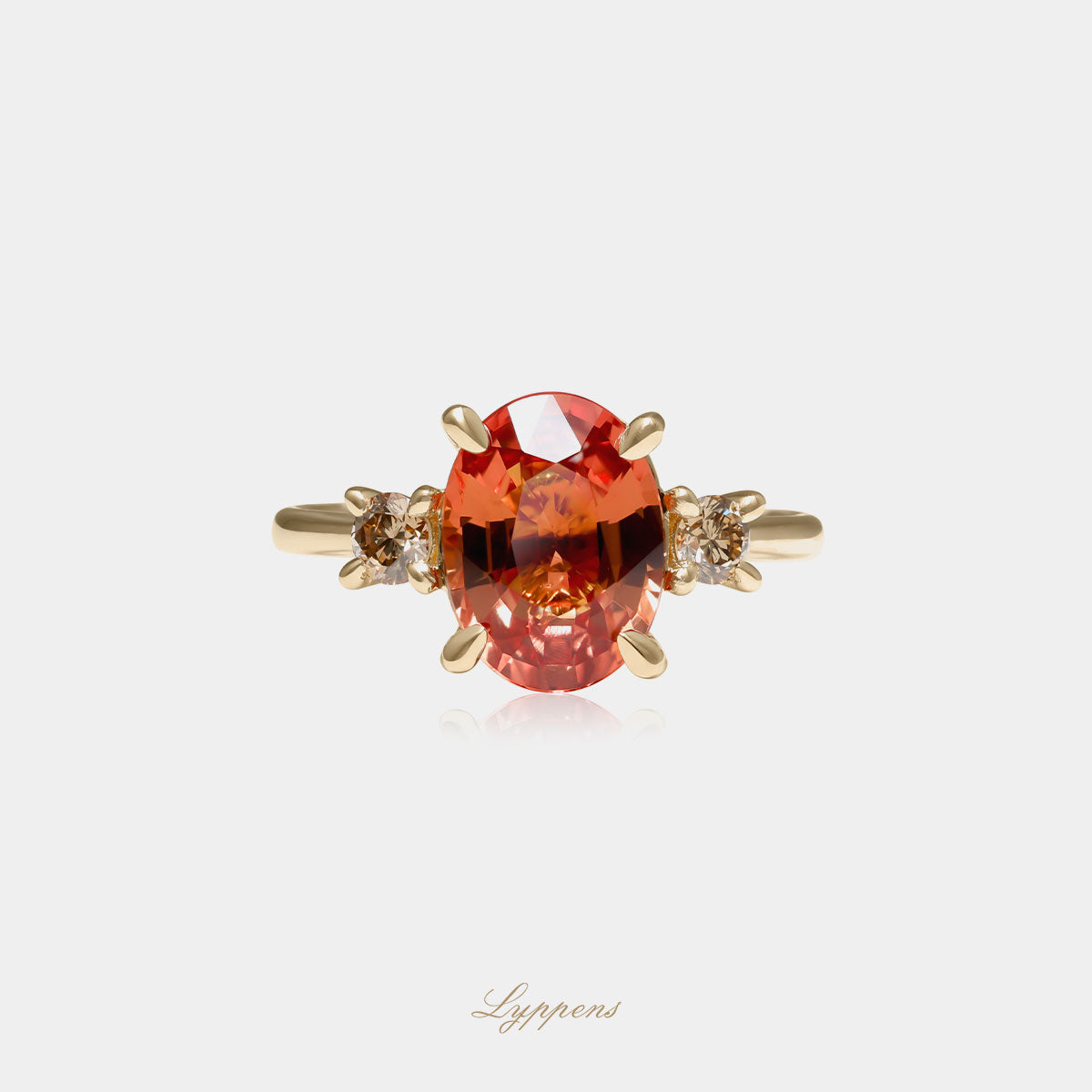 Geelgouden ring gezet met een ovaal geslepen oranje saffier en geflankeerd door briljant geslepen bruine diamant