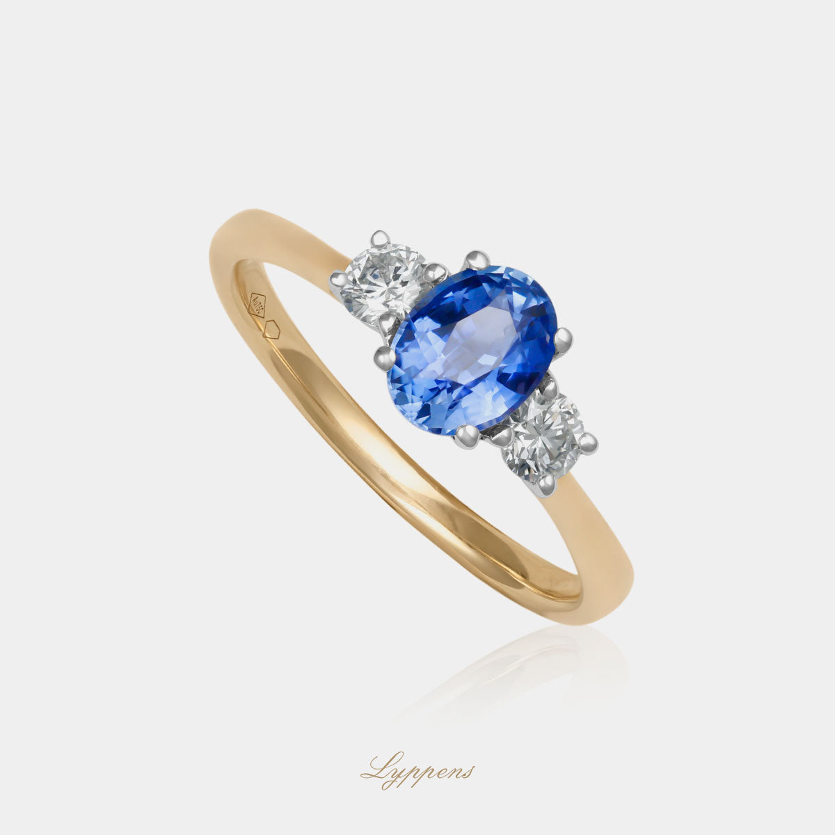 18kt geelgouden driesteens ring in het midden gezet met een ovaal geslepen saffier geflankeerd door briljant geslepen diamant.
