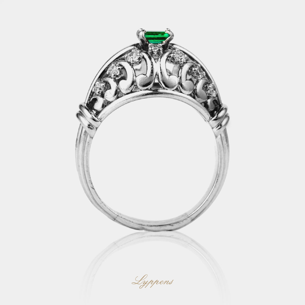 Witgouden vintage ring met smaragd en diamant in gekrulde elementen.