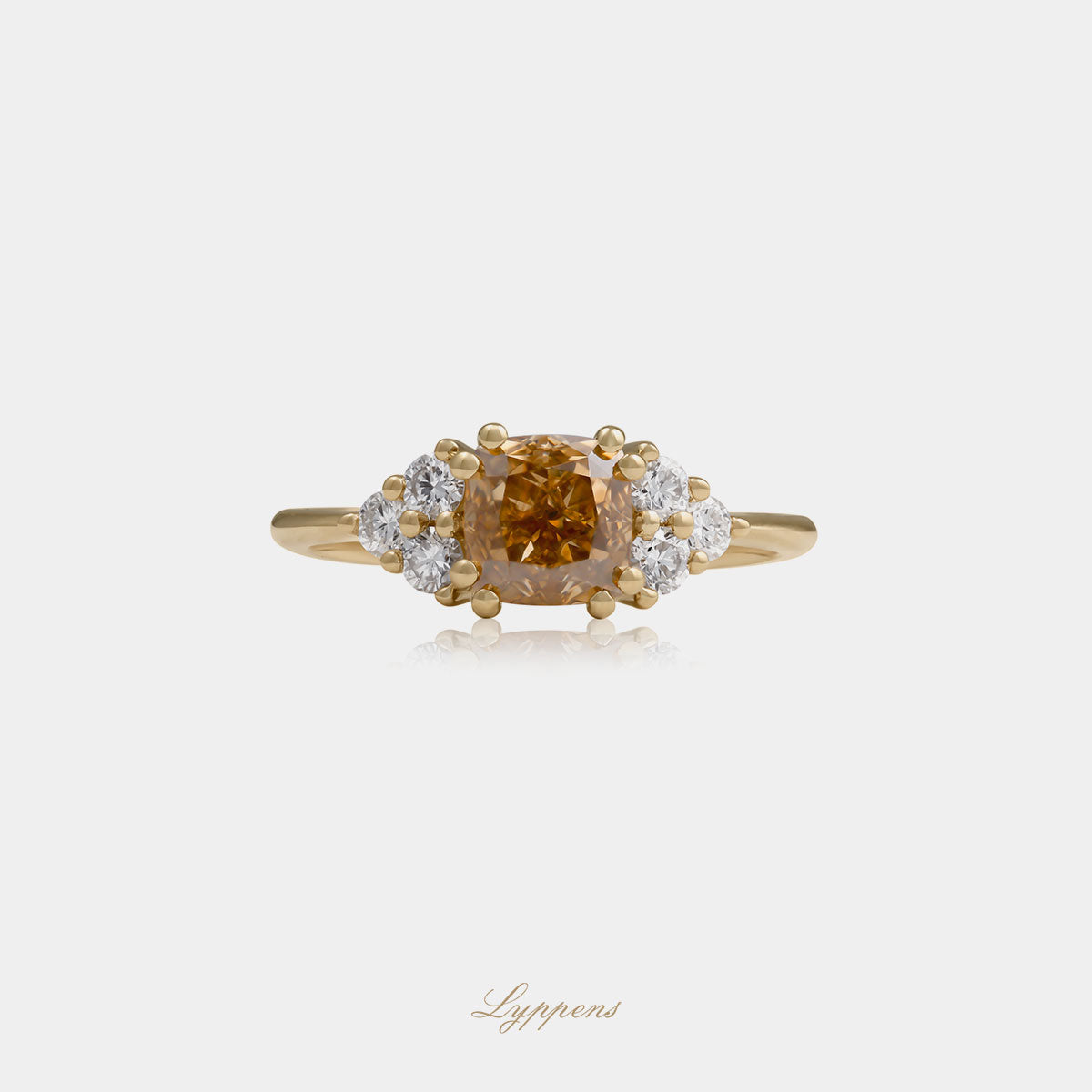 Geelgouden ring in het midden gezet met een cushion geslepen bruine diamant geflankeerd door briljant geslepen diamant.