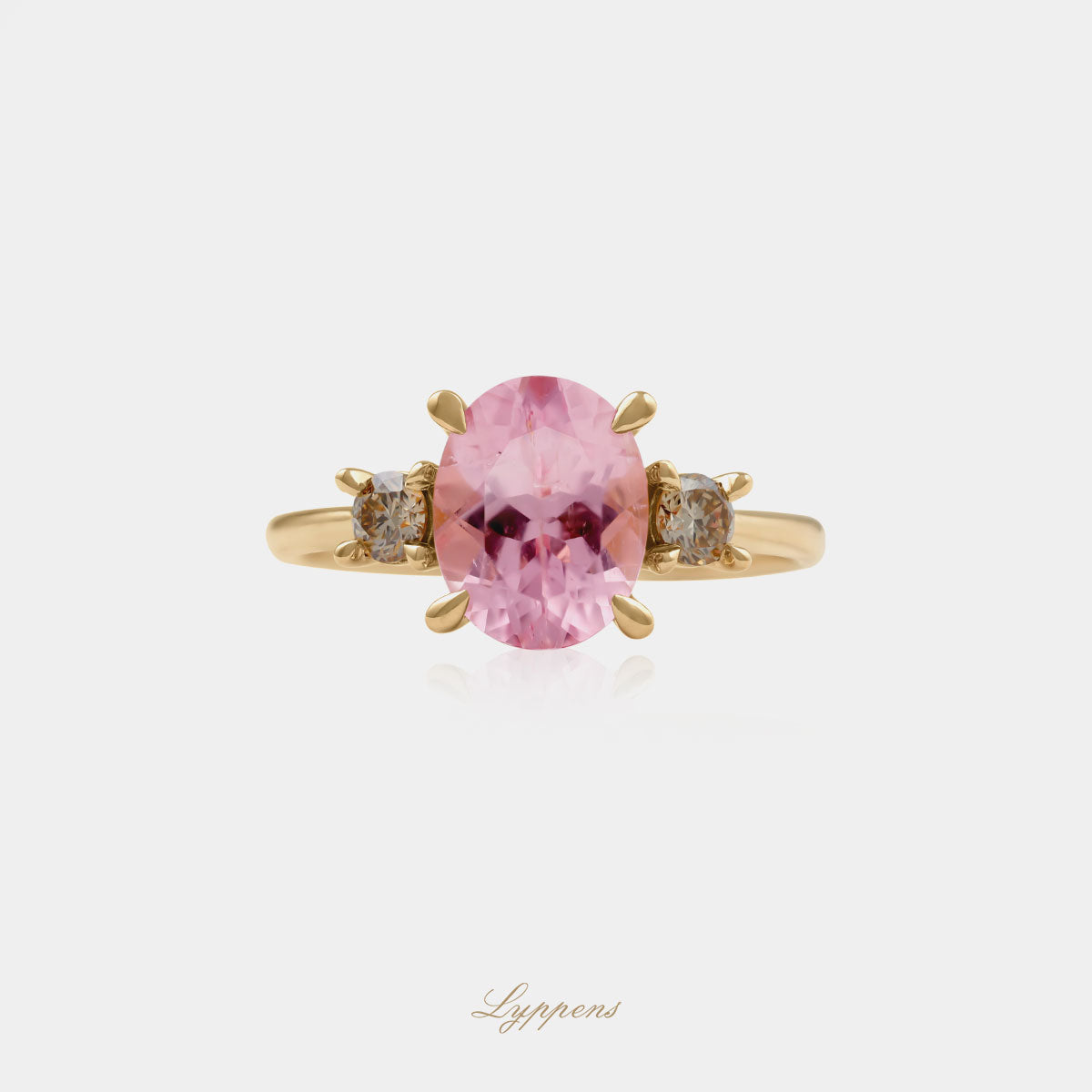 18kt geelgouden driesteensring in het midden gezet met een ovaal geslapen roze toermalijn geflankeerd door briljant geslepen bruine diamant.
