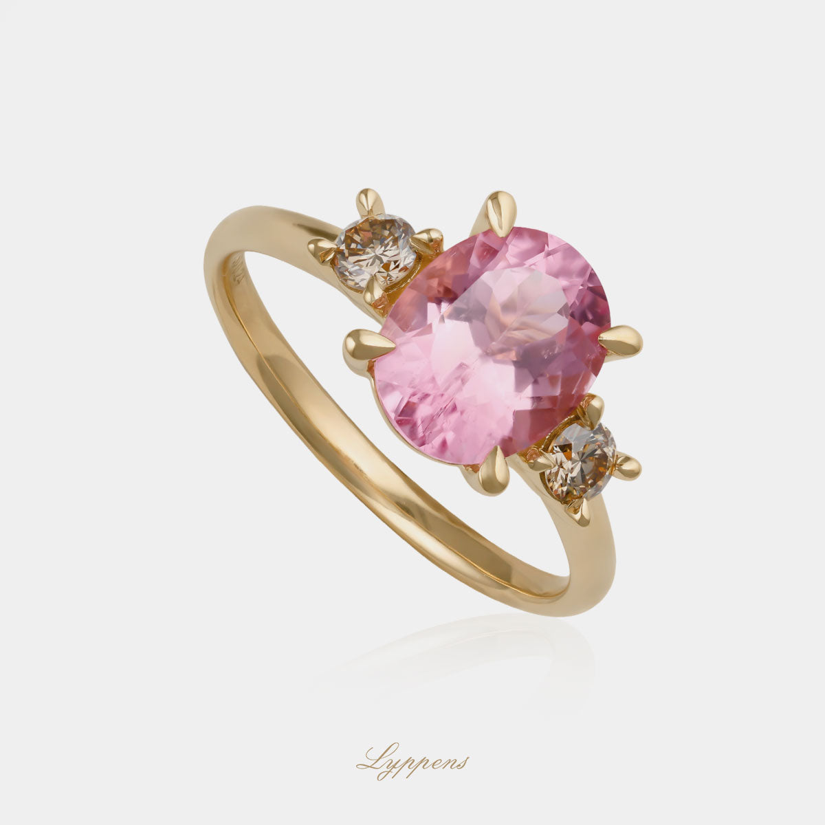 18kt geelgouden driesteensring in het midden gezet met een ovaal geslapen roze toermalijn geflankeerd door briljant geslepen bruine diamant.