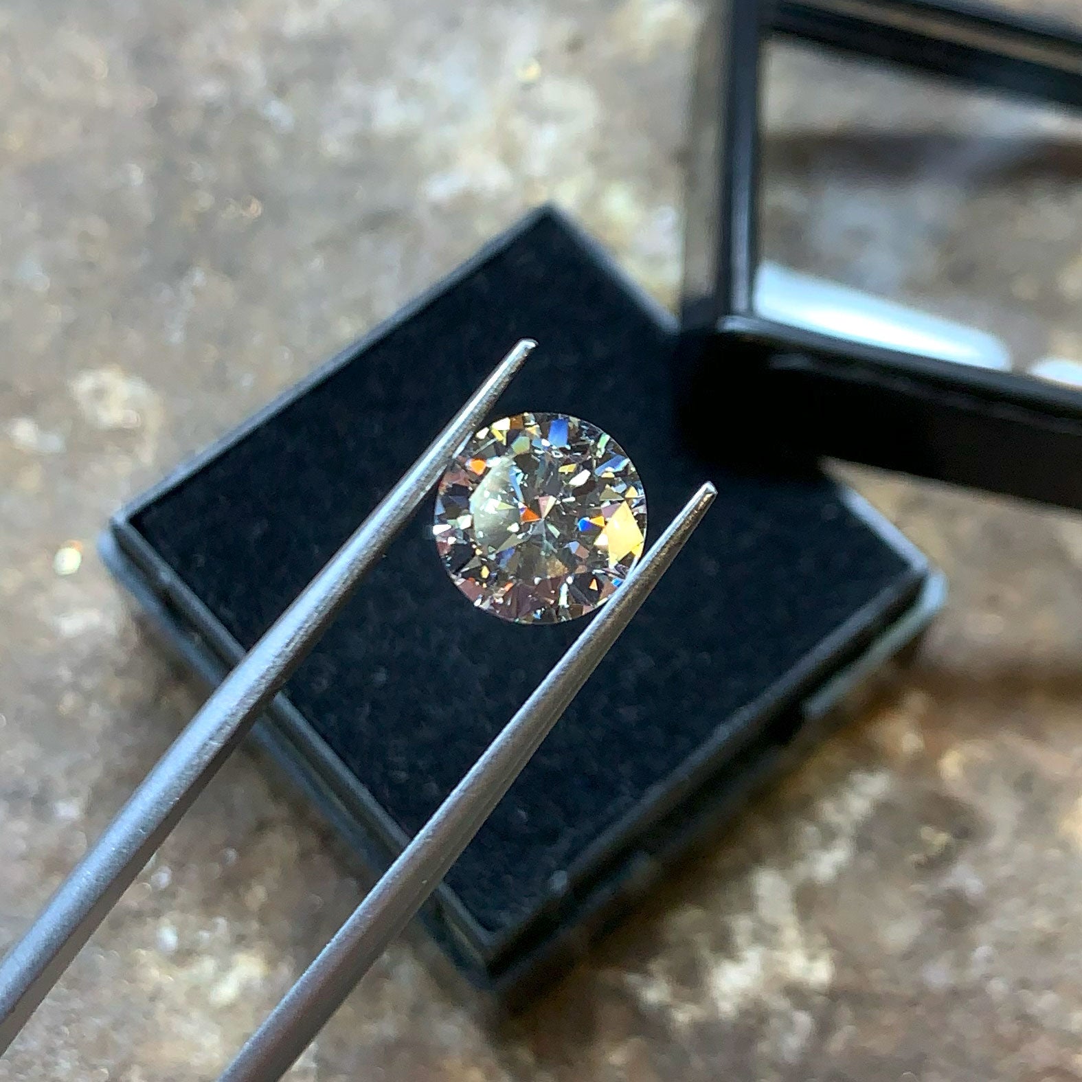 Losse briljant geslepen diamant tussen een pincet in het atelier.