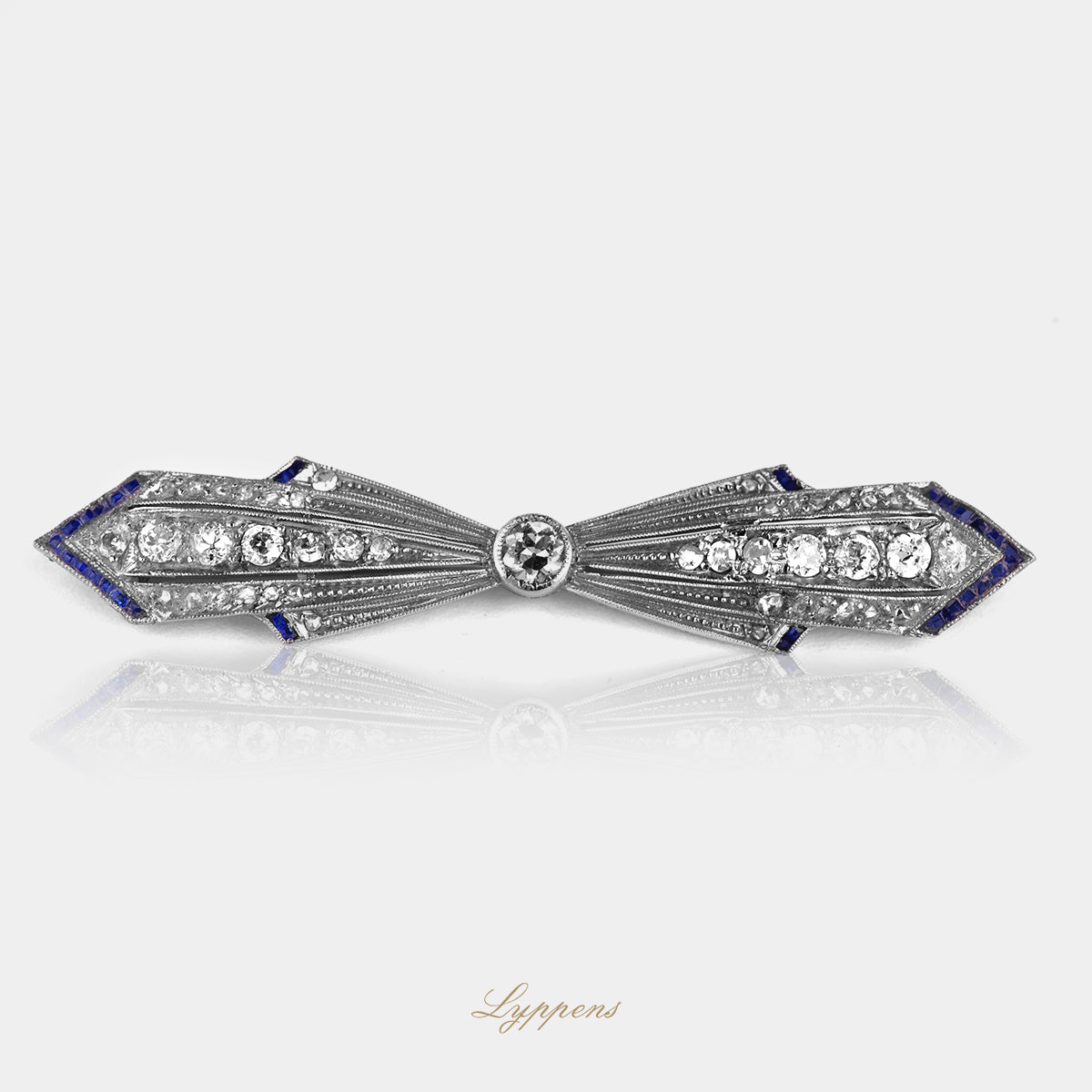 Platina strik vormige Art Deco brooch gezet met diamant en aan de uiteinde gezet met saffier.